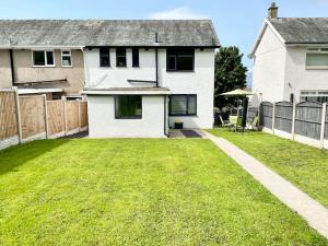 a yard with a white house and a fence at A modern, dog-friendly 3 bedrm canal side property in Bolton le Sands