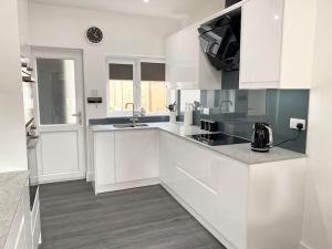 una cocina blanca con armarios blancos y fregadero en A modern, dog-friendly 3 bedrm canal side property en Bolton le Sands