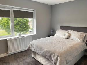 a white bedroom with a bed and two windows at A modern, dog-friendly 3 bedrm canal side property in Bolton le Sands