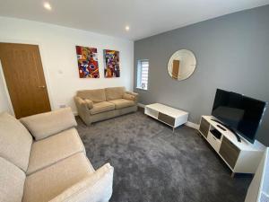a living room with a couch and a flat screen tv at A modern, dog-friendly 3 bedrm canal side property in Bolton le Sands