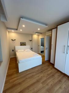a bedroom with a white bed and wooden floors at 3 min to beach, luxury building in Antalya