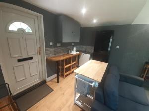 a living room with a blue couch and a kitchen at Ramblers Rest in Meopham