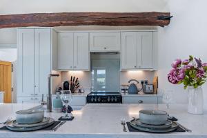 a kitchen with white cabinets and a table with two bowls at Dairy Barn by Bloom Stays in Groombridge