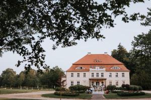 ein großes weißes Haus mit rotem Dach in der Unterkunft Pałac Bogaczów - hotel - restauracja in Bogaczów