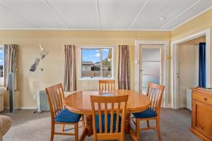 Un comedor con mesa y sillas de madera. en Lakeside Escape - Motuoapa Holiday Home, en Turangi