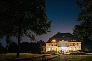 duży biały dom oświetlony nocą w obiekcie Pałac Bogaczów - hotel - restauracja w mieście Bogaczów