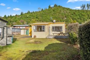 una casa pequeña con una montaña en el fondo en Lakeside Escape - Motuoapa Holiday Home, en Turangi