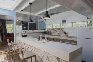 a kitchen with a white counter top and chairs at Villa Branca - Les Terres Basses in Marigot