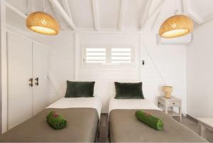 two beds in a white room with two green pillows at Villa Branca - Les Terres Basses in Marigot