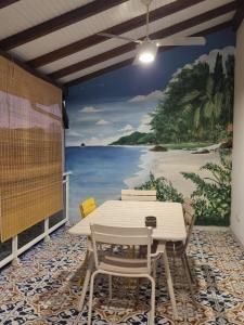 een tafel en stoelen voor een muurschildering van een strand bij Villa Stone pour 8 personnes, piscine chauffée, accès PMR, 5 étoiles in Sainte-Luce