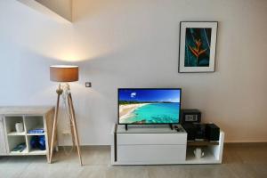 a living room with a flat screen tv on a white cabinet at Appartement Seacret in Baie Nettle