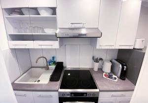 uma pequena cozinha branca com um fogão e um lavatório em NOVA Apartment- Phantasialand I Köln I Bonn em Brühl