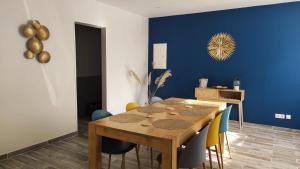 een eetkamer met een houten tafel en een blauwe muur bij Bulles d'Evasion in Avize