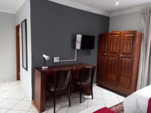 a bedroom with a desk with chairs and a bed at REALJOY GUEST SUITES in Centurion