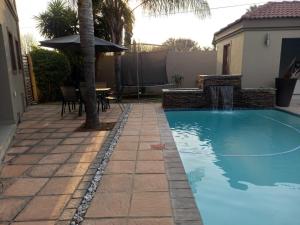 a swimming pool with a table and an umbrella at REALJOY GUEST SUITES in Centurion