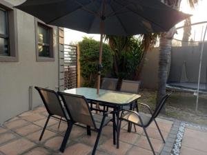 a table and chairs with an umbrella on a patio at REALJOY GUEST SUITES in Centurion