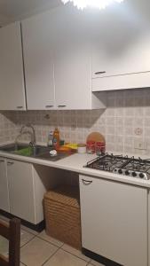 kuchnia z białymi szafkami, zlewem i kuchenką w obiekcie CONDOMINIO MAURIZIO A MARE w mieście Scerne