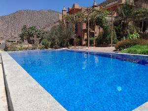 a large blue swimming pool in front of a house at Dar Tamounte in Tagadirt nʼBour