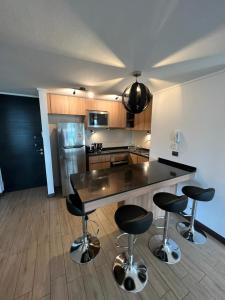eine Küche mit einer Theke und 4 Barhockern in der Unterkunft 2 dormitorios a pasos de la CLC in Santiago