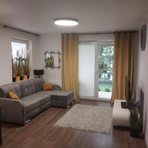 a living room with a couch and a tv at Apartament w Bursztynowych Komnatach in Darłówko