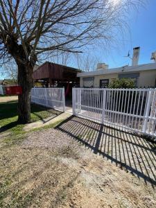 una cerca blanca frente a una casa con un árbol en MARVIR en Alvorada, en Barra del Chuy