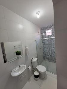 a white bathroom with a toilet and a sink at Pousada Águas Marinhas in Maceió