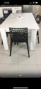un tavolo bianco con una sedia nera seduta intorno di Maison vue mer Al Hoceïma ad Al-Ḥoseyma