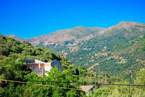 a building on a hill with mountains in the background at Rias's Place in Kalamiós