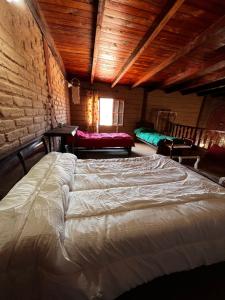 a large bed in a room with a brick wall at Cabaña Bethsabet Cafayate Salta in Cafayate