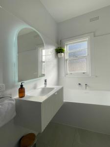 a white bathroom with a sink and a mirror at Bella Vista on Beach in Hobart