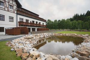 uma parede de pedra em torno de um lago em frente a um edifício em Strunzova pila - wellness em Kvilda