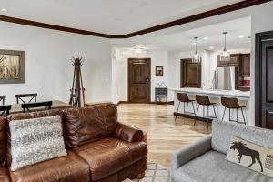 a living room with a leather couch and a kitchen at Comfort at Arrowhead Village - Steps from the lift condo in Edwards