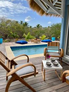 a deck with chairs and a table next to a pool at Villa Branca - Les Terres Basses in Marigot