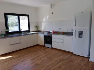cocina con electrodomésticos blancos y suelo de madera en Casa de campo DON ANTONIO en San Pedro