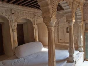 RāmgarhNarayan Niwas Castle的一张带白色床垫的床,坐在房间里