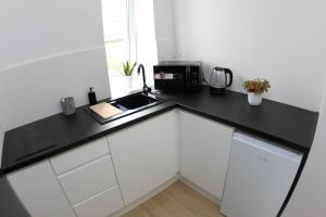a kitchen with white cabinets and a black counter top at Komfi Dom 4 in Rzeszów