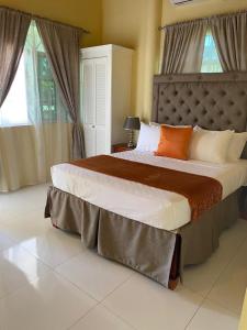 a bedroom with a large bed with orange and white pillows at Runthings Hideaway Stay Negril in Negril