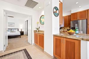 una cocina con armarios de madera y una habitación con cama en K B M Resorts- KGV-14V3 Oversized 2Bdrm sweeping ocean views remodeled premium upgrades, en Kapalua