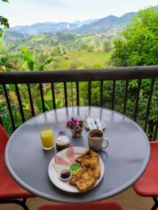 a table with a plate of breakfast food on a balcony at Hotel Villa Palosanto in Jericó