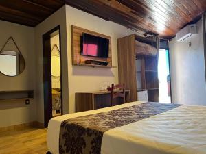a bedroom with a bed and a tv on the wall at Pousada Serra Geral in Cambará