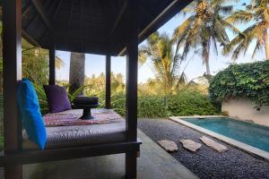 a bed in a gazebo next to a swimming pool at Temuku Villas Ubud - CHSE Certified in Ubud