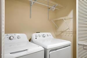 a laundry room with two white washes and a drying rack at K B M Resorts KRO L201 Stunning Remodeled 2B Villa at Kaanapali Royal with Ocean Views and free Rental car in Lahaina