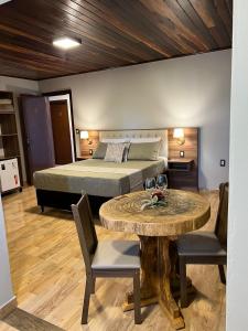 a bedroom with a bed and a table and a bed at Pousada Serra Geral in Cambara do Sul