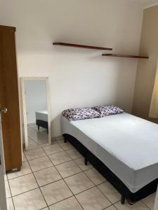 a bedroom with a bed and a mirror on the wall at Apartamento lindo em Ubatuba - Centro in Ubatuba