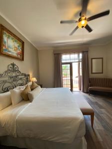 a bedroom with a large white bed with a ceiling fan at Casa Lucia Hotel Boutique in Mérida