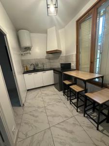 eine Küche mit einem Tisch, Stühlen und einem Waschbecken in der Unterkunft Appartement mignon in Livry-Gargan