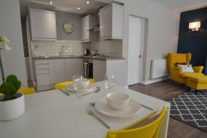 a kitchen and dining room with a white table and yellow chairs at Charming 1 bed riverside apartment in Chester