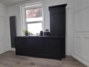 a black cabinet in a room with a window at Chic 5 double bedroom house - 15 min to Manchester in Manchester