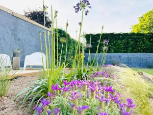 un jardín con flores púrpuras frente a una valla en La Suite (Ô) Wood & Chic, en Cucq