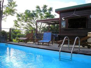 a swimming pool with two chairs and a house at Bakoulélé en Guadeloupe in Bouillante
